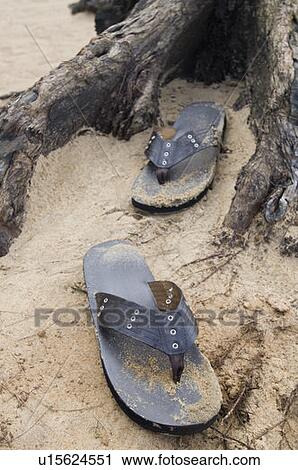 Stock Image - Close-up of a pair of flip-flops on the beach. Fotosearch