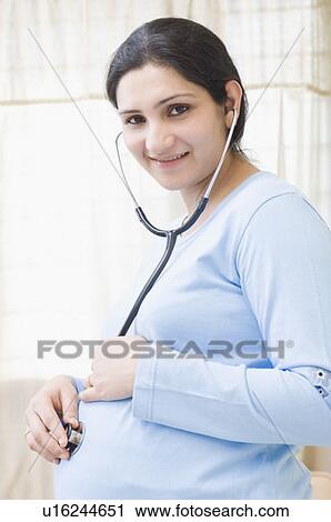 Close-up of a pregnant woman putting a stethoscope on her abdomen View Large Photo Image Stock Image - Close-up of a pregnant woman putting a stethoscope on her abdomen. Fotosearch