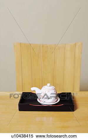 Stock Photography - Close-up of a tea kettle in a tray on the table. Fotosearch