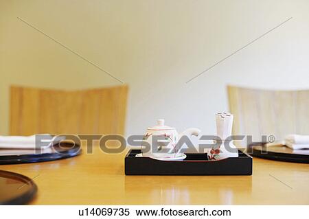 Stock Photography - Close-up of a tea kettle with a tray on the table. Fotosearch