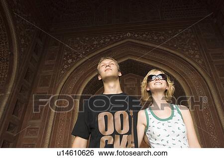 Stock Photograph - Close-up of a young couple standing and smiling, Taj Mahal, Agra, Uttar Pradesh, India. Fotosearch