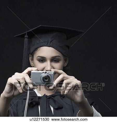 Stock Image - Close-up of a young female graduate holding a digital camera. Fotosearch