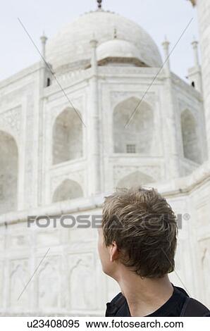 Stock Photography - Close-up of a young man looking at a mausoleum, Taj Mahal, Agra, Uttar Pradesh, India. Fotosearch