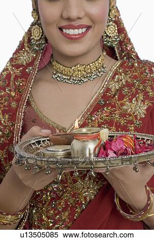 Stock Photography - Close-up of a young woman holding a plate of religious offerings. Fotosearch