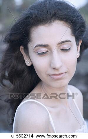 Picture - Close-up of a young woman thinking with her eyes closed. Fotosearch
