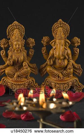 Stock Photograph - Close-up of an oil lamp burning in front of religious idols. Fotosearch