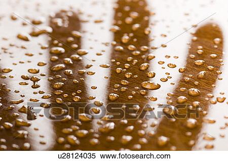 Stock Photography - Close-up of shadow of a human hand with water drops on brown surface. Fotosearch