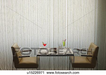 Stock Image - Close-up of two empty chairs and a table in a restaurant. Fotosearch