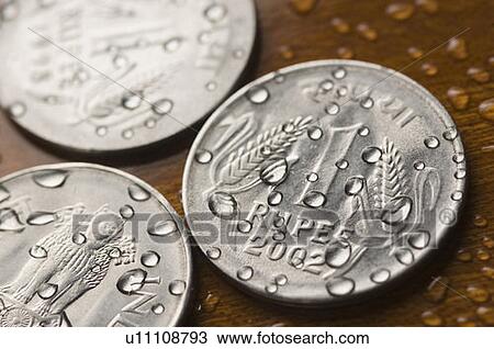 Stock Image - Close-up of water droplets on Indian one rupee coins. Fotosearch