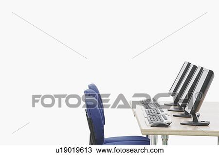 Stock Image - Computer on a table in front of chairs. Fotosearch