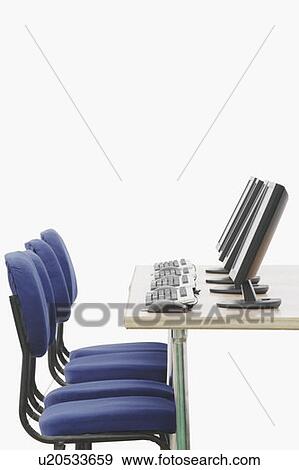 Stock Photo - Computer on a table in front of chairs. Fotosearch