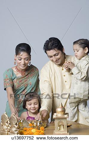 Stock Image - Couple decorating a pooja thali with their children. Fotosearch