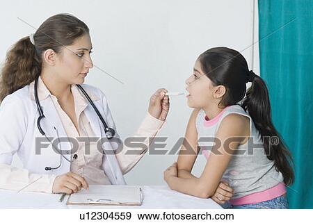 Female doctor measuring fever of a girl View Large Photo Image Stock Photo - Female doctor measuring fever of a girl. Fotosearch