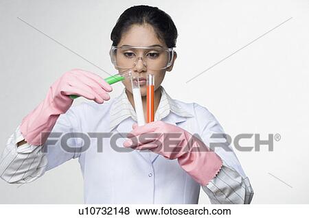 Female scientist pouring liquid from a test tube into another test tube in a laboratory View Large Photo Image Stock Photo - Female scientist pouring liquid from a test tube into another test tube in a laboratory. Fotosearch