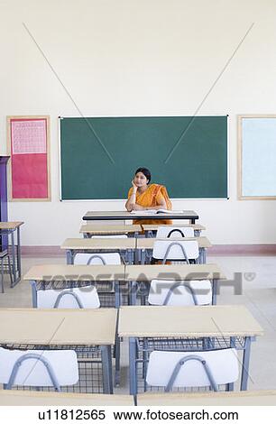 Stock Photography - Female teacher sitting in an empty classroom. Fotosearch