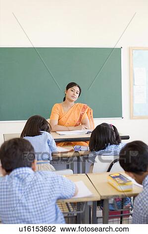 Stock Image - Female teacher teaching her students in a classroom. Fotosearch