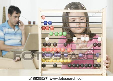 Girl playing with an abacus with her father talking on a mobile phone in the background View Large Photo Image Stock Photo - Girl playing with an abacus with her father talking on a mobile phone in the background. Fotosearch