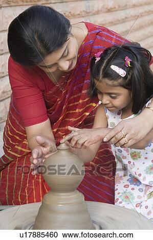 Stock Image - Girl with her teacher in a pottery class. Fotosearch