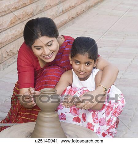 Stock Image - Girl with her teacher in a pottery class. Fotosearch