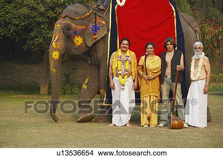 Picture - Group of people standing beside an elephant. Fotosearch