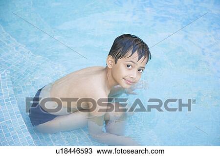 Stock Image - High angle view of a boy sitting on a step of a swimming pool. Fotosearch