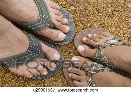 Stock Photo - High angle view of a couple's feet wearing flip-flops. Fotosearch