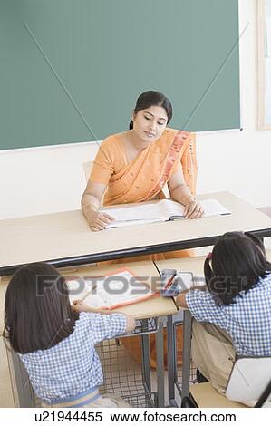 Stock Photography - High angle view of a teacher and schoolgirls sitting in a classroom. Fotosearch
