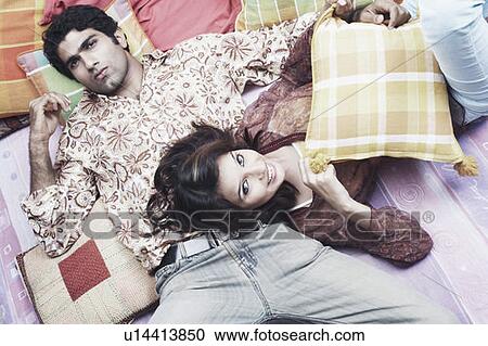 Stock Image - High angle view of a young woman lying on a young man's stomach. Fotosearch