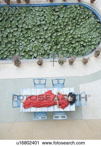 High angle view of a young woman lying on a table View Large Photo Image Stock Image - High angle view of a young woman lying on a table. Fotosearch
