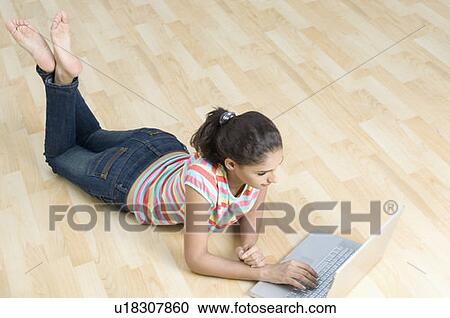 High angle view of a young woman lying on the floor and using a laptop View Large Photo Image Stock Image - High angle view of a young woman lying on the floor and using a laptop. Fotosearch