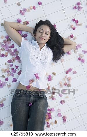 High angle view of a young woman lying on the floor with her hands behind her head View Large Photo Image Stock Image - High angle view of a young woman lying on the floor with her hands behind her head. Fotosearch