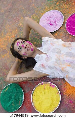 Stock Photo - High angle view of a young woman lying down with plates of powder paint around her. Fotosearch