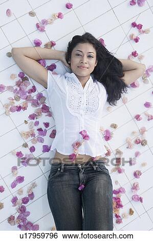 Stock Photograph - High angle view of a young woman lying on the floor with her hands behind her head. Fotosearch