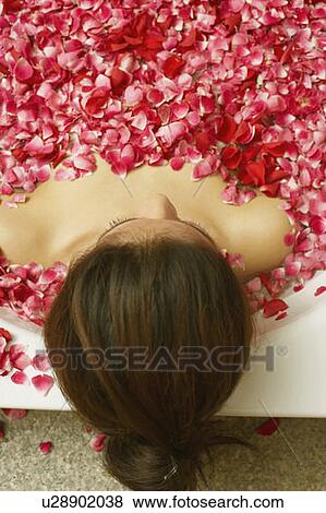 Stock Photo - High angle view of a young woman reclining in a bathtub full of rose petals. Fotosearch