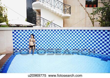 Stock Photography - High angle view of a young woman standing in a swimming pool. Fotosearch