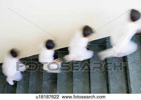 Stock Image - High angle view of four children running on a staircase. Fotosearch