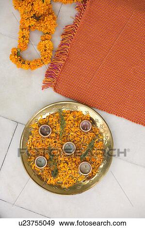 Stock Photo - High angle view of oil lamps with petals of Marigolds on a plate. Fotosearch