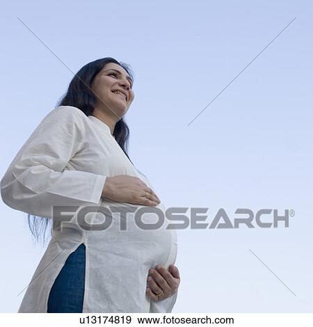 Low angle view of a pregnant woman smiling View Large Photo Image Stock Photo - Low angle view of a pregnant woman smiling. Fotosearch