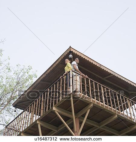 Low angle view of a young couple standing at the railing of a log cabin View Large Photo Image Stock Image - Low angle view of a young couple standing at the railing of a log cabin. Fotosearch