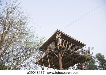 Stock Photo - Low angle view of a young couple standing at the railing of a log cabin. Fotosearch