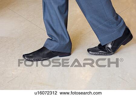 Stock Image - Low section view of a man walking. Fotosearch