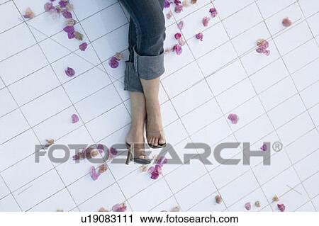 Stock Image - Low section view of a woman's legs on the tiled floor. Fotosearch