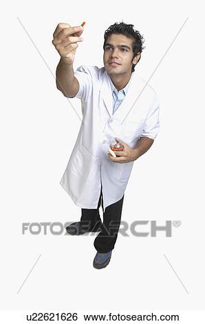 Stock Photograph - Male doctor holding a pill bottle and a capsule. Fotosearch