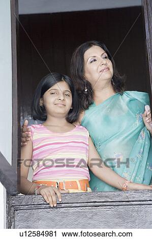 Stock Image - Mature woman with her daughter standing at a window. Fotosearch