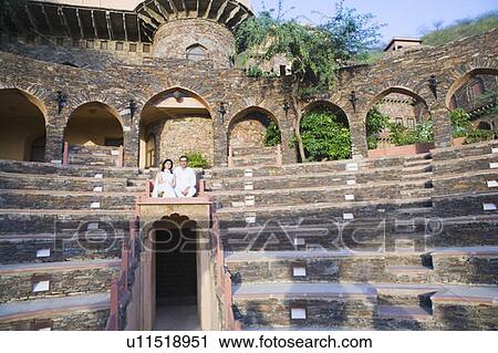 Stock Image - Mid adult couple sitting on steps. Fotosearch