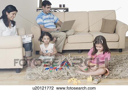 Stock Image - Mid adult couple with their two daughters in a living room. Fotosearch