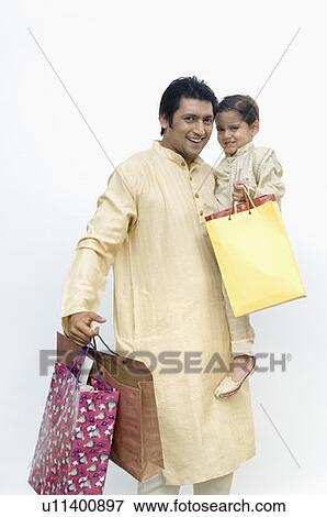 Stock Photo - Mid adult man carrying his son and holding shopping bags. Fotosearch
