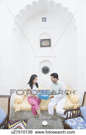 Mid adult man giving a gift to a mid adult woman and smiling View Large Photo Image Stock Photo - Mid adult man giving a gift to a mid adult woman and smiling. Fotosearch