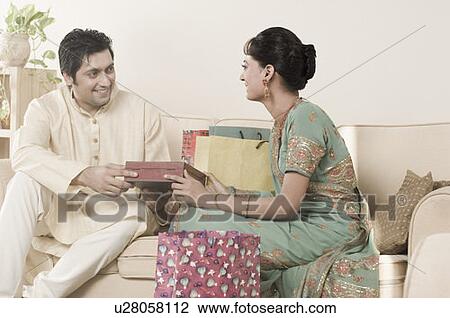 Stock Image - Mid adult man giving a gift to a young woman. Fotosearch