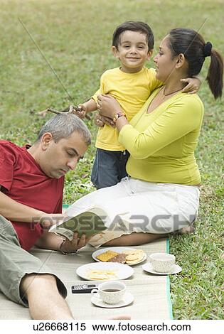 Stock Photography - Mid adult man reading a book and a mid adult woman hugging her son. Fotosearch